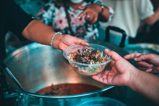Concept of giving free food to the poor in the community : Volunteers handing out food to hungry people